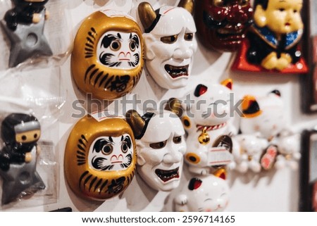 Traditional Japanese tourist souvenirs and gifts from Kyoto, Kansai, Japan, with daruma figures, kitsune fox, tengu mask, fridge magnets, toys figurines, key ring keychain, in a local vendor gift shop