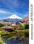 A traditional Japanese village with cherry blossom gardens, ponds, and views of Mount Fuji as a backdrop. in Japan