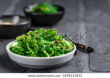 Traditional Japanese wakame salad with sesam seeds on black background. Healthy and fresh seaweed salad.
