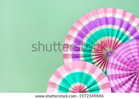 Traditional Japaneses festival paper fan with pink, turquoise, white stripes on green background Birthday party, celebration holidays concept Abstract background Wall decor