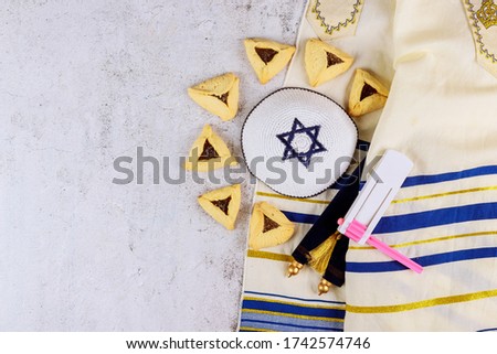 Traditional jewish carnival holiday Purim celebration and hamantaschen cookies, noisemaker and mask, holy book, talit, kippa