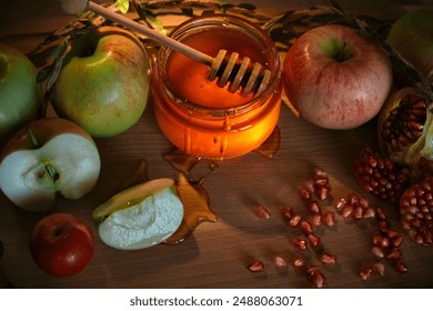 Traditional Jewish new year food. Happy Rosh Hashanah concept. Red and green apples, pomegranate and seeds and honey in a glass jar on wooden background.