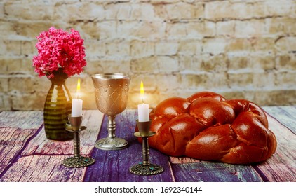 Traditional Jewish Sabbath Shalom ritual fresh challah bread with kiddush cup of red kosher wine