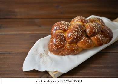 Traditional Jewish sweet Challah bread for Shabbat on a wood plate on wooden table, with copy space 