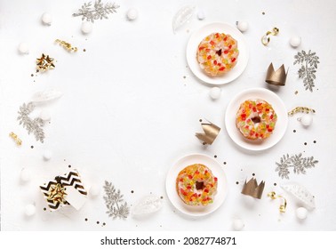 Traditional kings day bread Epiphany cake on white background with winter decorations. Roscon de reyes, spanish three kings Christmas sweet cake. Spanish typical dessert of Epiphany day, top view.