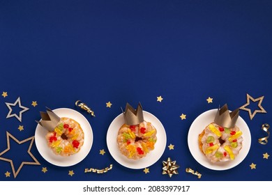 Traditional kings day bread Epiphany cakes on blue background with winter decorations. Roscon de reyes, spanish three kings Christmas sweet cake. Spanish typical dessert of Epiphany day, top view.