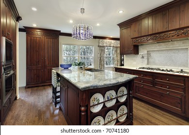 Traditional Kitchen With Dark Wood Cabinetry And Granite Island