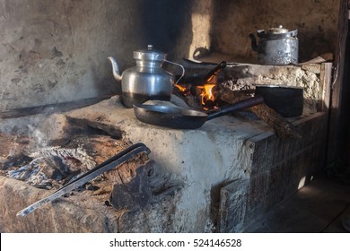 Traditional Kitchen In Old Nepali House In Small Remote Village In Himalayas With Open Fire Place, Smoking Coal, Kettles, Frying Pans And Pots. Interior Of A Poor Asian House.