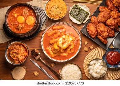 Traditional Korean food, Korean Fried chicken with spicy sauce  with rice, seaweed,fresh raw crabs marinated,spicy Rice Cake and Kimchi pickle on wooden table. - Shutterstock ID 2105787773