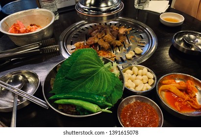 Traditional Korean Pork And Beef BBQ On The Wooden Round Table With Movable Cooker Hood