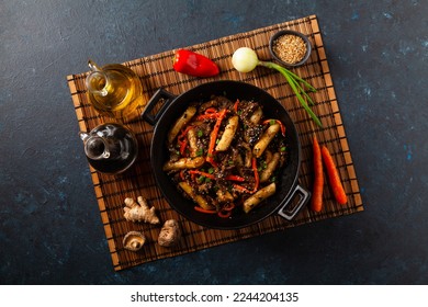 Traditional Korean Tteokbokki rice noodles with beef, vegetables and shitake mushrooms. Prepared in a wok. Dark blue background. 