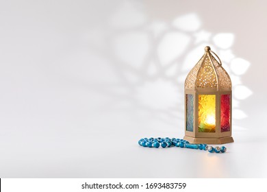 Traditional Lantern And Luxury Rosary Beads On A White Background With Arabesque Shadow Effect.