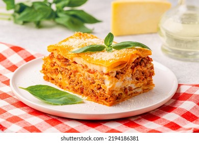 Traditional lasagna with bolognese sauce topped with basil leaves served on a white plate - Shutterstock ID 2194186381