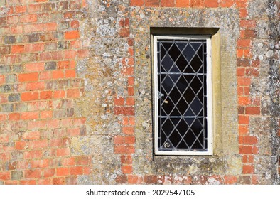 a traditional leaded lights window in the exterior wall of an old brick building 