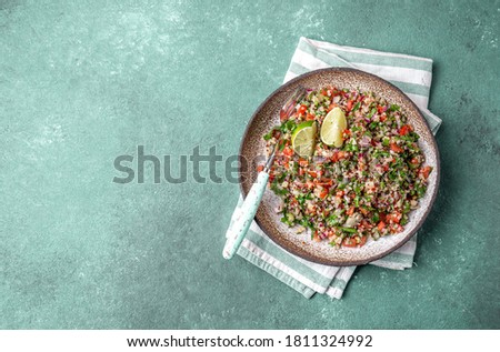 Traditional Lebanese salad tabouli tabule with quinoa, herbs, tomatoes, mint and lemon.