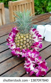 A Traditional Lei Wrapped Around A Pineappl On A Table At A Polynesian Luau