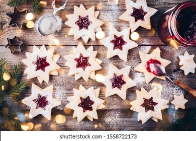 Traditional Linzer Christmas cookies filled with raspberry jam on wooden background.
