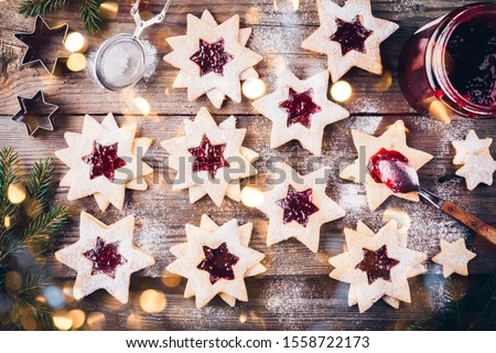 Traditional Linzer Christmas cookies filled with raspberry jam on wooden background.