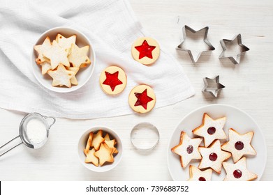 Traditional Linzer cookies - stars with red jam and cranberry on the white wooden table. Christmas and New Year pastry.