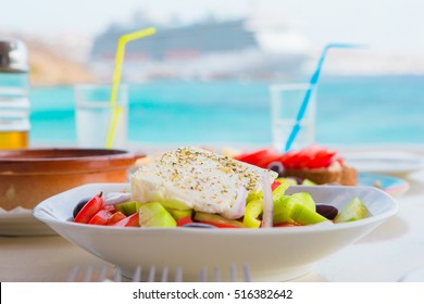 Traditional lunch with delicious fresh greek salad and brusketa served for lunch at outdoor restaurant with beautiful view on the sea and port