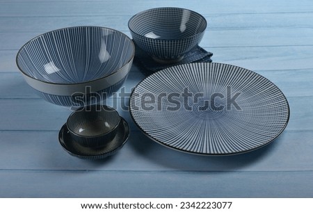 traditional luxury utensil dine ware Japanese ceramic china blue art drawing sakura flower design round big small gloss plate bowl w cloth and chopstick on blue wood table background