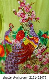 Traditional Malay Batik Kebaya or Baba Nyonya dress with beautiful floral and peacock embroidery displayed upright on stand. Selective focus image.