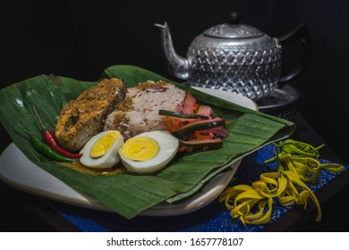 Traditional Malaysian nasi dagang, or rice steamed in coconut milk, served with fish curry and boiled eggs on a green leaf