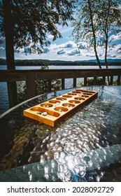 Traditional Mancala boardgame with glass pieces with tranquil lake background