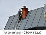 Traditional manual method of cleaning the chimney on the roof