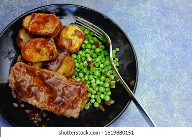 Traditional Meat Loaf Dinner With Gravy Roast Potatoes And Green Peas. Shot From Above