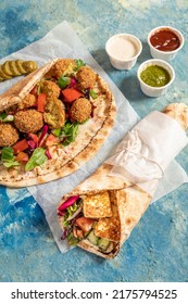 Traditional Mediterranean Arabic Grilled Halloumi And Falafel, Hummus And Vegetables In Flatbread Wraps With Herbs And A Variety Of Sauces