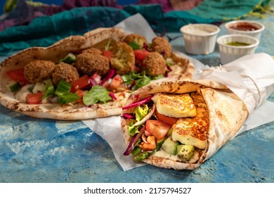 Traditional Mediterranean Arabic Grilled Halloumi And Falafel, Hummus And Vegetables In Flatbread Wraps With Herbs And A Variety Of Sauces