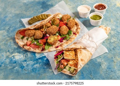 Traditional Mediterranean Arabic Grilled Halloumi And Falafel, Hummus And Vegetables In Flatbread Wraps With Herbs And A Variety Of Sauces