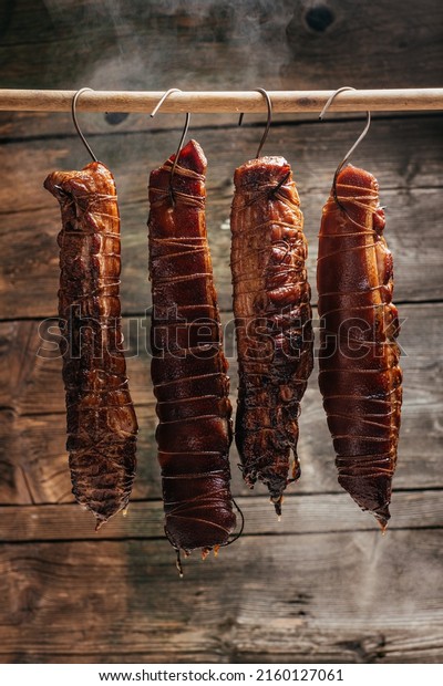 Traditional method of smoking\
meat in smoke. Smoked ham, bacon, pork neck and sausages in a\
smokehouse.