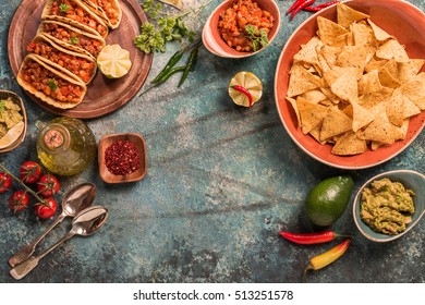 traditional mexican food - tacos with meat, beans and salsa and nachos with sauce. Top view