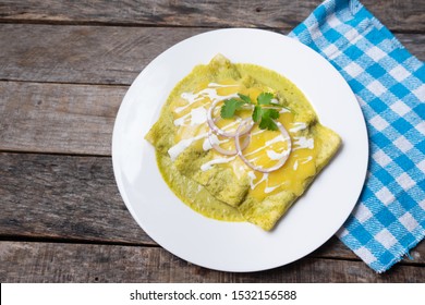 Traditional mexican green enchiladas with melted cheese also called "suizas" on wooden background - Shutterstock ID 1532156588
