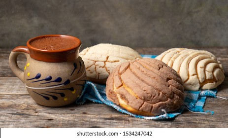 Traditional mexican hot chocolate with sweet conchas bread on wooden background