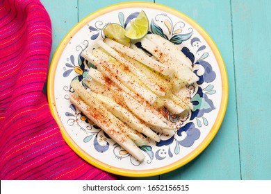 Traditional mexican jicama and cucumber cutted with chili powder on turquoise background