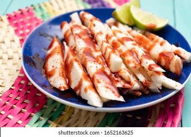 Traditional mexican jicama  cutted with chili powder and piquant sauce on turquoise background