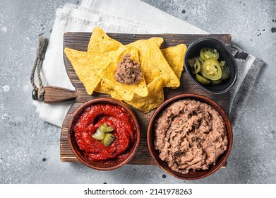 Traditional Mexican Refried Beans With Nachos, Jalapeno And Tomato Sauce. Wooden Background. Top View.