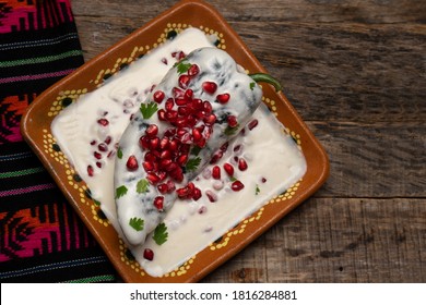 Traditional mexican stuffed poblano peppers also called nogada with pomegranate on wooden background