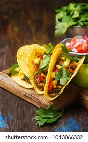 Traditional Mexican tacos with tomatoes, meat, herbs. Dark background. Fast food