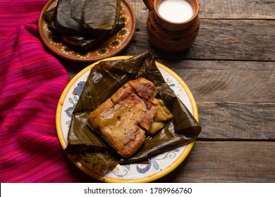 Traditional mexican tamales in banana leaves on wooden background
