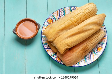 Traditional mexican tamales with red sauce on turquoise  background
