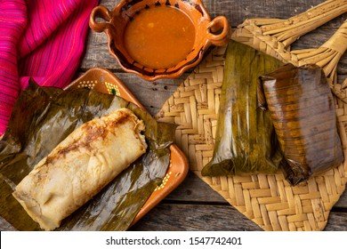 Traditional mexican tamales wrapped in banana leaves also called "oaxaqueños" on wooden background