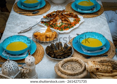 Traditional Middle Eastern dinner table set with soup, grilled chicken, samosas, stuffed grape leaves, and fresh bread, showcasing authentic Arabic cuisine and hospitality.