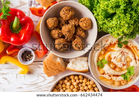 Traditional middle eastern homemade dishes falafel, pita, hummus and chickpea served with vegetables and spices on woodwn table. Top view