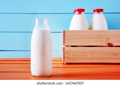 Traditional Milk Bottle In Front Of A Wooden Crate Full Of Milk Bottles On A Wooden Country Kitchen Table 