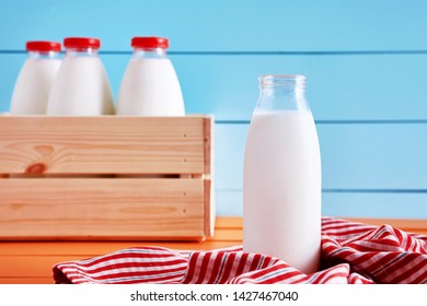 Traditional Milk Bottle In Front Of A Wooden Crate Full Of Milk Bottles On A Wooden Country Kitchen Table 