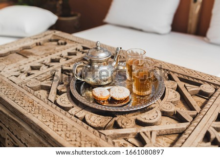 Traditional moroccan mint tea with cookies on silver tray on carved wooden table. Beautiful vintage style, hospitality in Morocco.